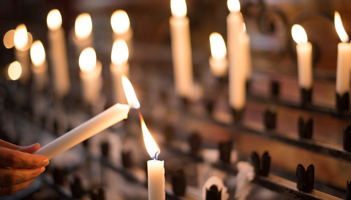 Woman lighting candle in a historic church, enhancing spiritual tour experience.