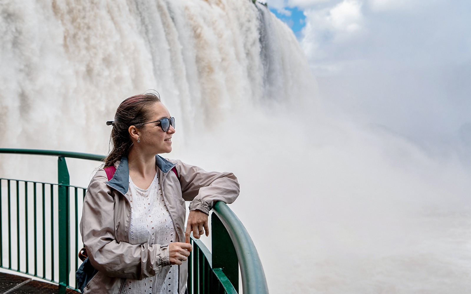 Visitors observing Iguazu Falls from the Argentine side, with lush greenery and cascading water.