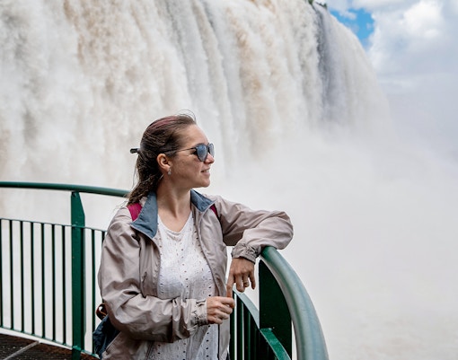 Visitors observing Iguazu Falls from the Argentine side, with lush greenery and cascading water.