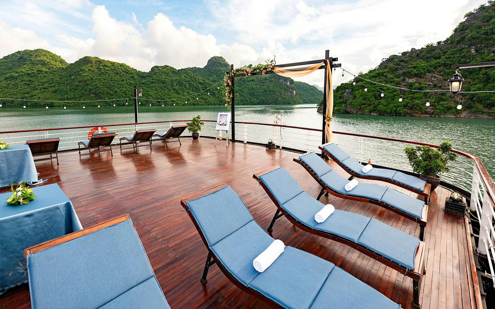 Outdoor deck with lounge chairs overlooking scenic bay and green hills.