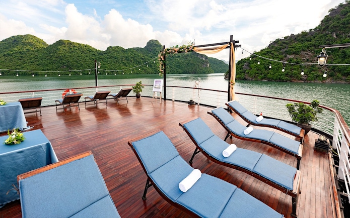 Outdoor deck with lounge chairs overlooking scenic bay and green hills.
