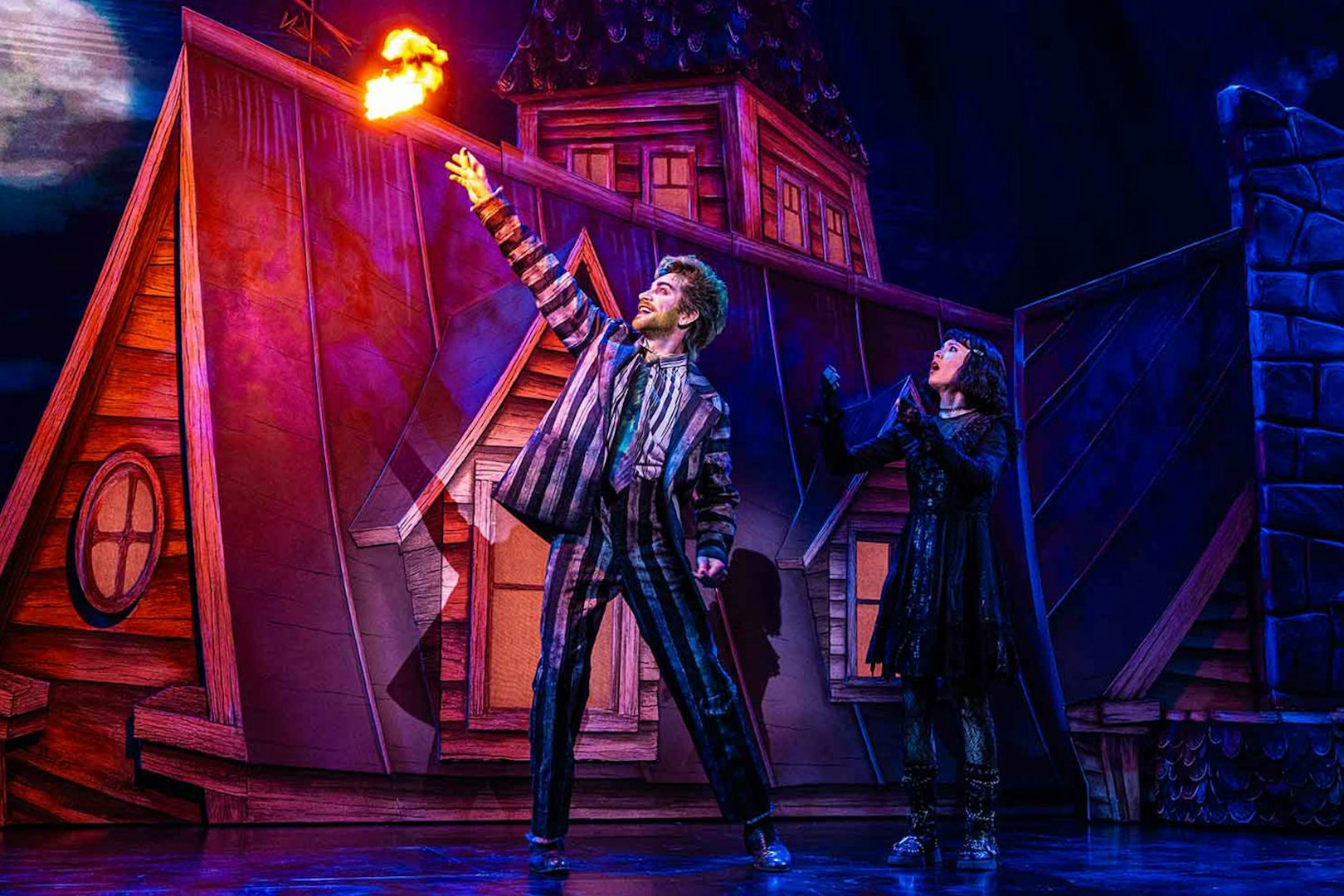 Stage scene from Beetlejuice show in Brisbane with characters on a rooftop.