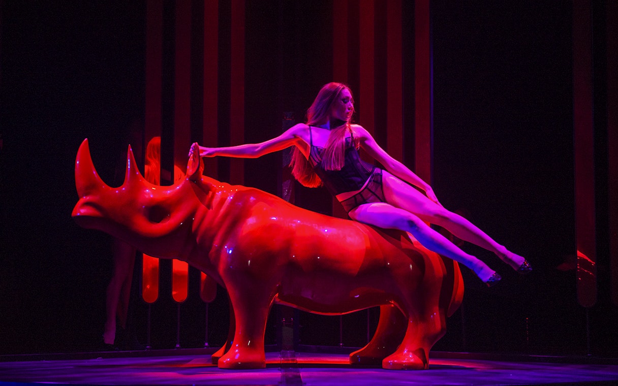 Performer on red rhinoceros sculpture at Paradis Latin festive show.