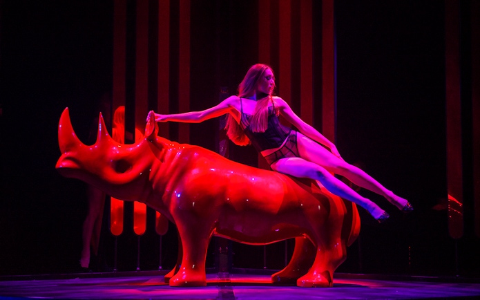Performer on red rhinoceros sculpture at Paradis Latin festive show.