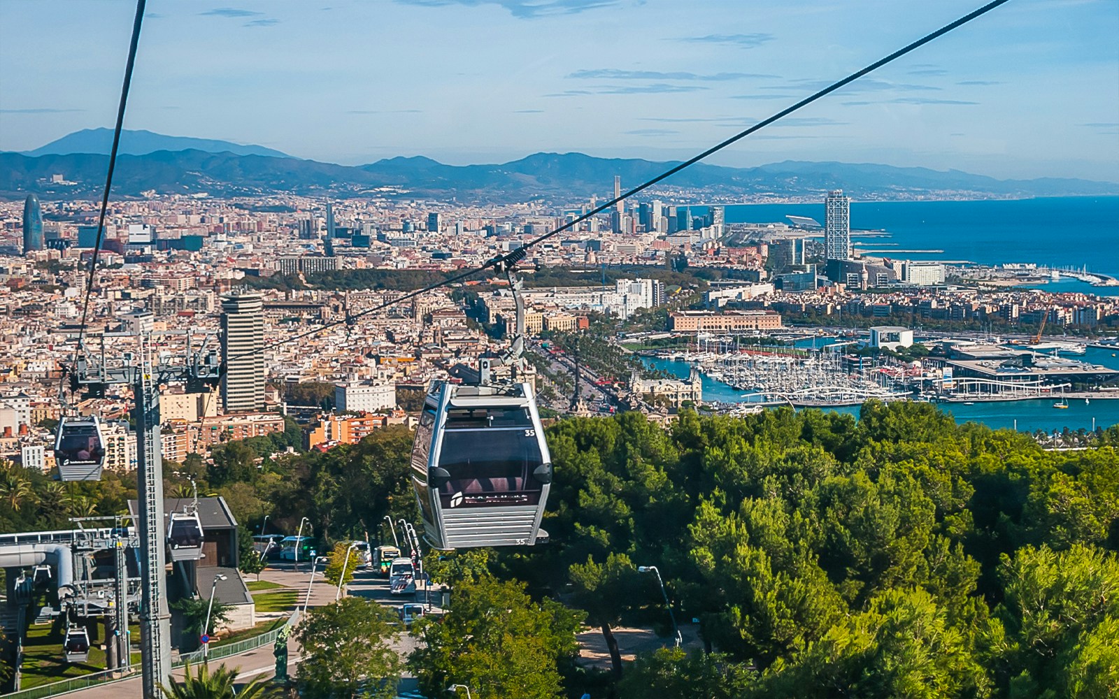 Montjuic Cable Car ascending with panoramic view of Barcelona cityscape.