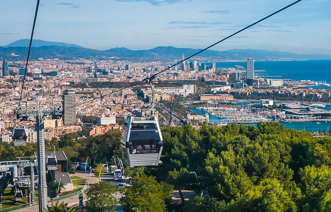 Montjuic Cable Car ascending with panoramic view of Barcelona cityscape.