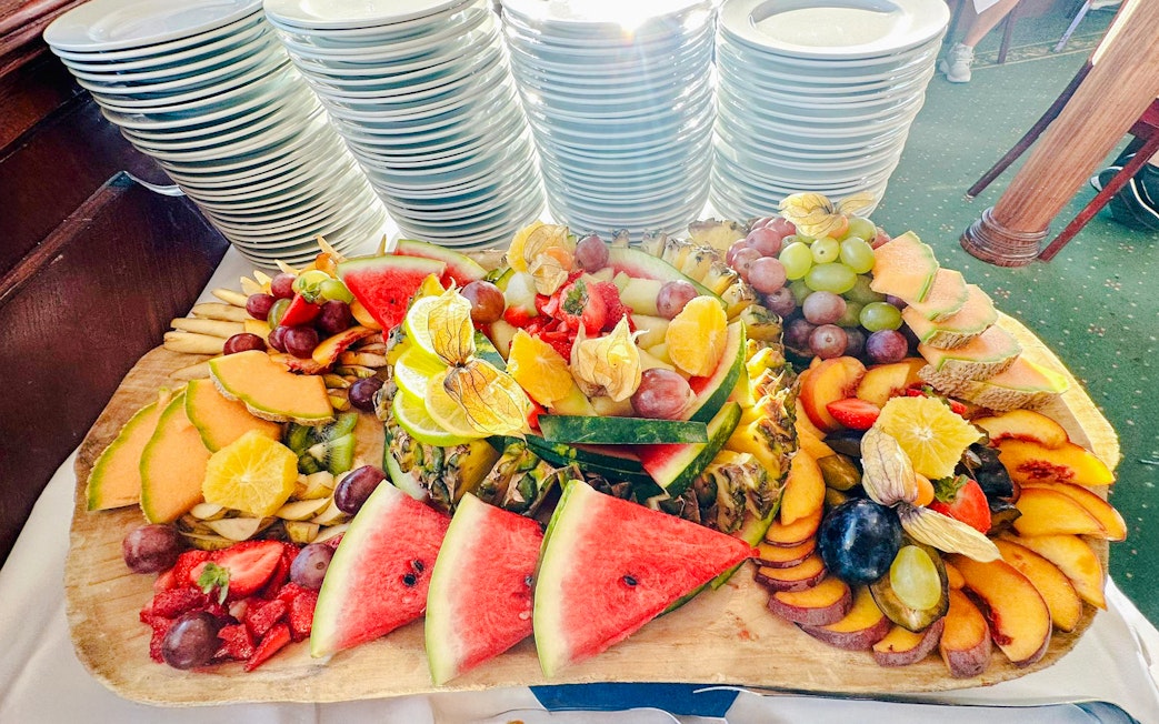 Fruit salad buffet on Sunshine Booze Cruise, Budapest, featuring watermelon, grapes, and citrus slices.