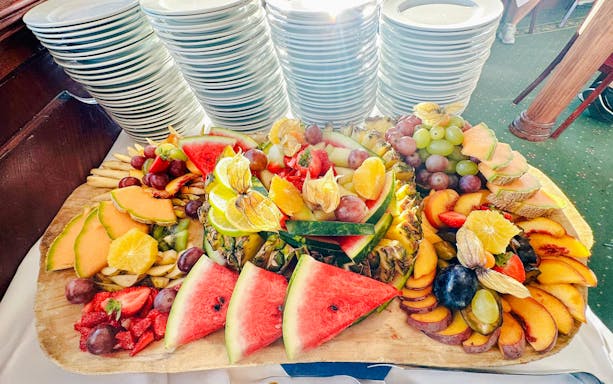 Fruit salad buffet on Sunshine Booze Cruise, Budapest, featuring watermelon, grapes, and citrus slices.