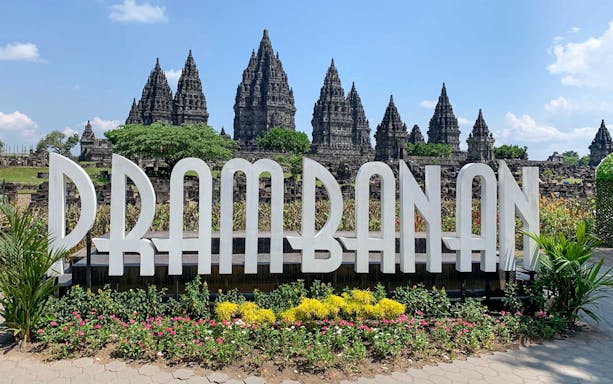 Prambanan Temple complex with large sign and surrounding gardens in Yogyakarta, Indonesia.