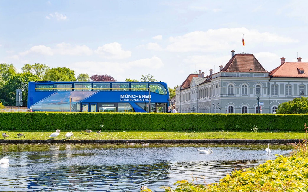 Munich hop-on hop-off bus near Nymphenburg Palace with swans in the foreground.