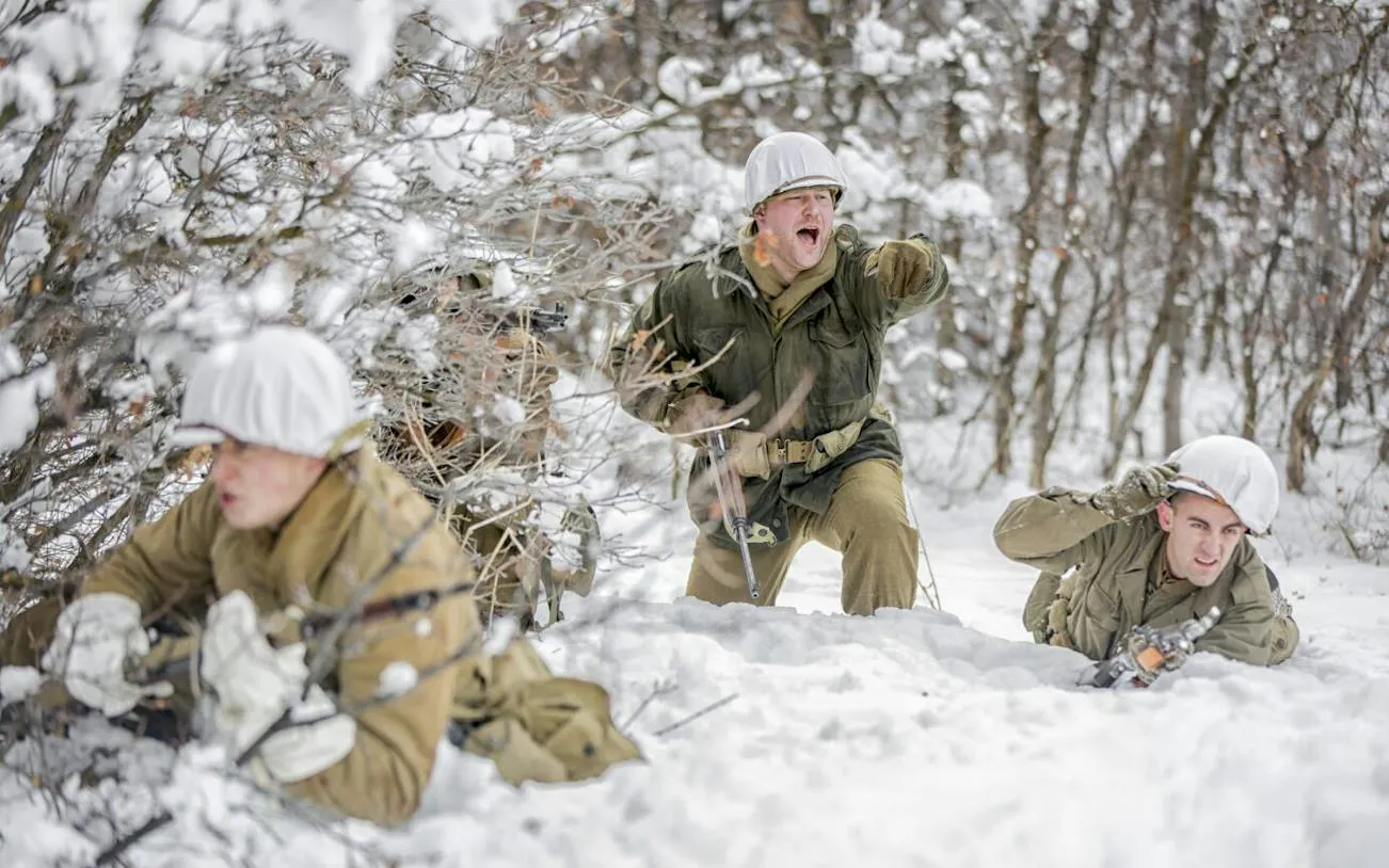 Soldiers reenact Battle of the Bulge in snowy forest, part of Brussels tour with Bastogne War Museum.