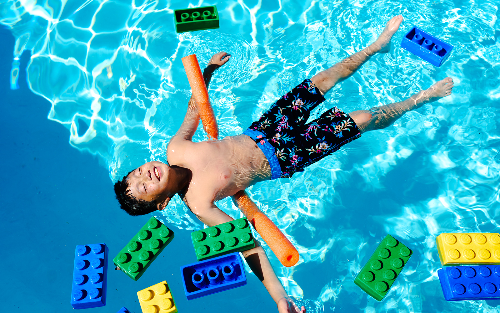 Child floating in pool with large LEGO bricks at Water Playground, Legoland New York.