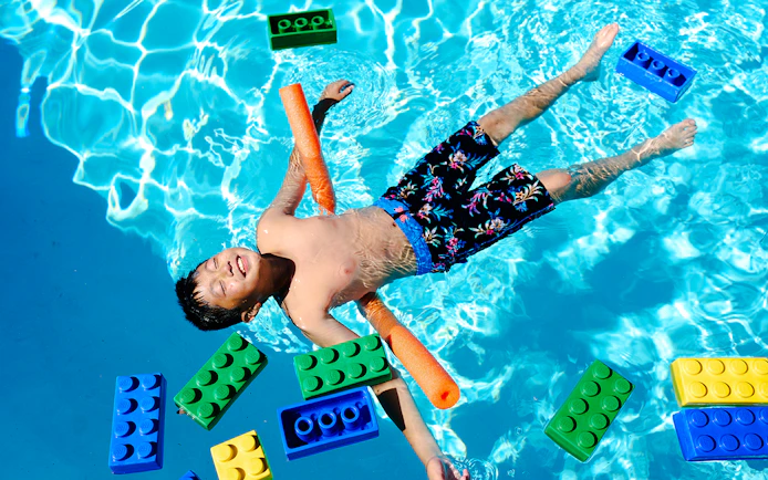 Child floating in pool with large LEGO bricks at Water Playground, Legoland New York.