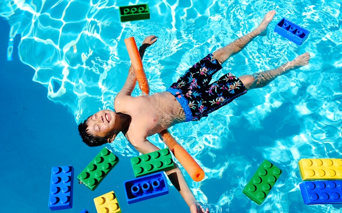 Child floating in pool with large LEGO bricks at Water Playground, Legoland New York.