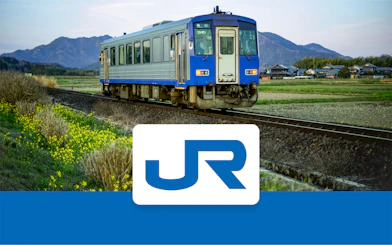 JR-West train traveling through rural Kansai with mountains in the background.