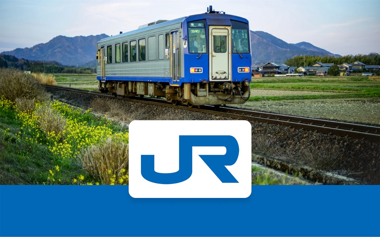 JR-West train traveling through rural Kansai with mountains in the background.