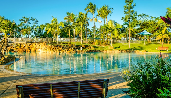 Lagoon swimming pool surrounded by lush greenery at a hotel.