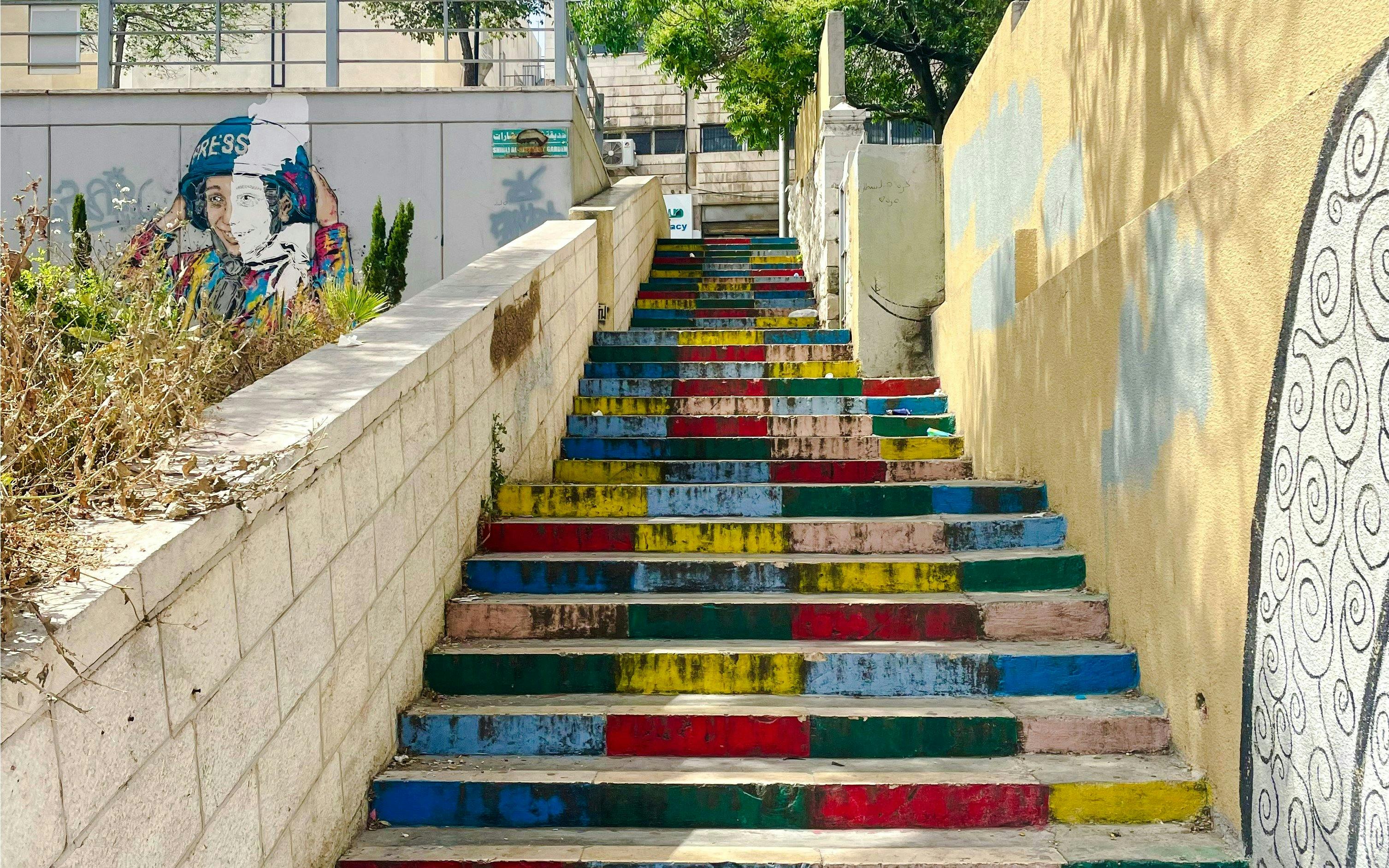 Colorful stairs on Rainbow Street, Amman, Jordan, with vibrant wall art.