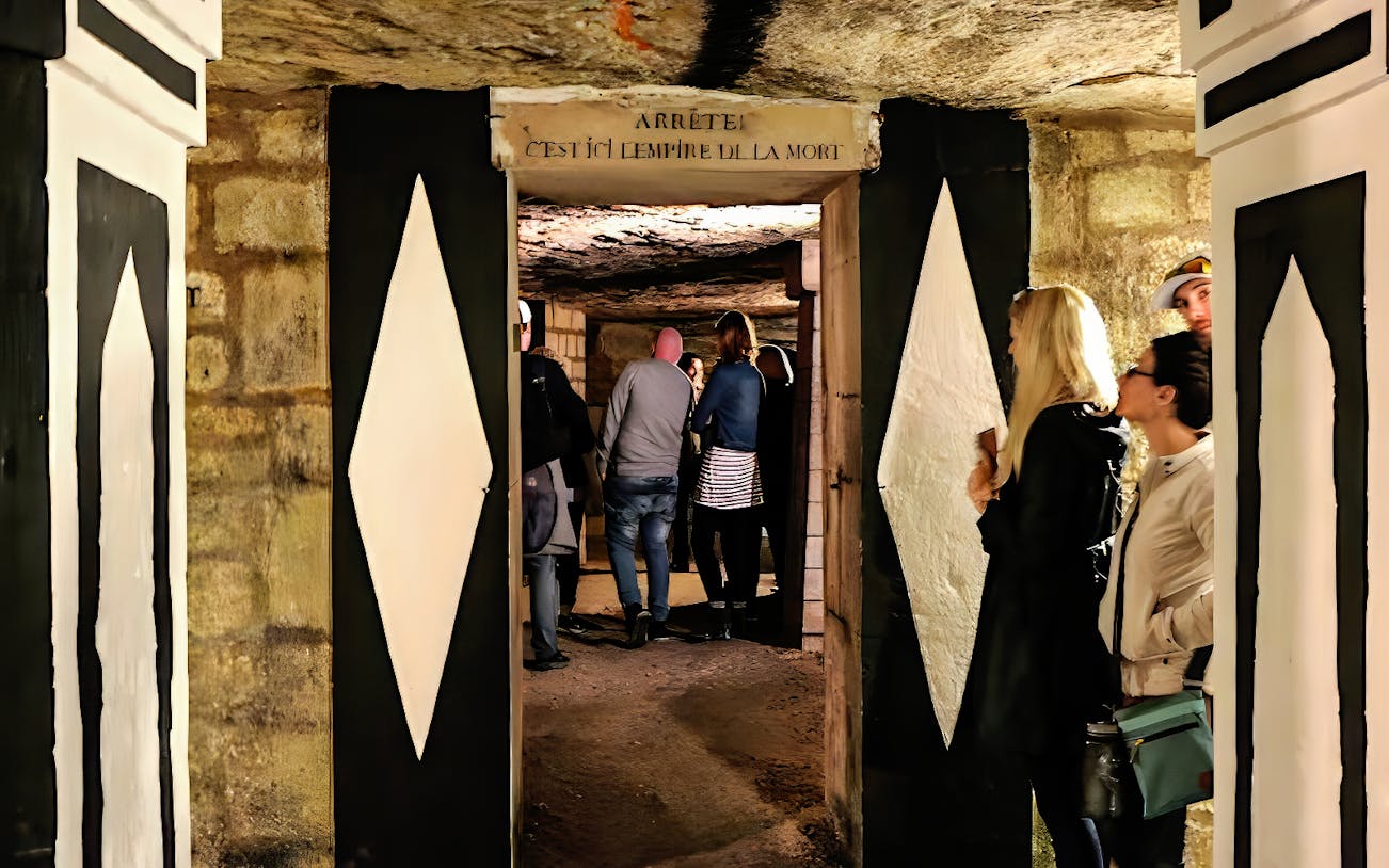Tour group exploring the Paris Catacombs through a narrow passage.