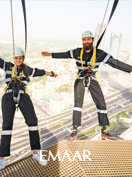 Visitors on Sky Views Edge Walk with Dubai skyline in background.