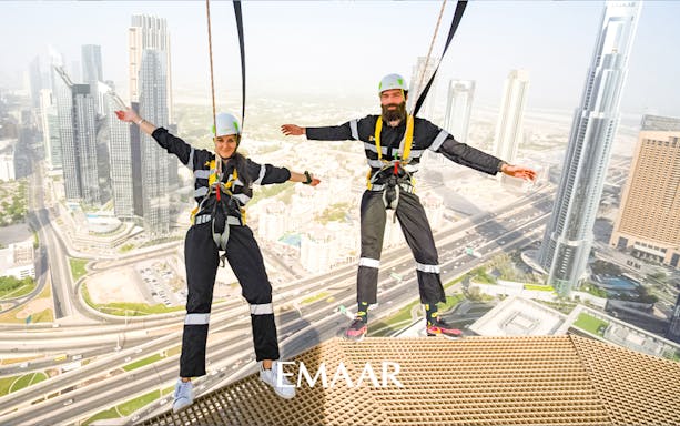 Visitors on Sky Views Edge Walk with Dubai skyline in background.