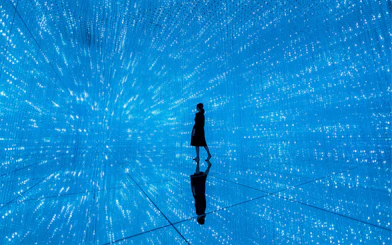 Person walking through digital light installation at TeamLab Planets Tokyo exhibit.