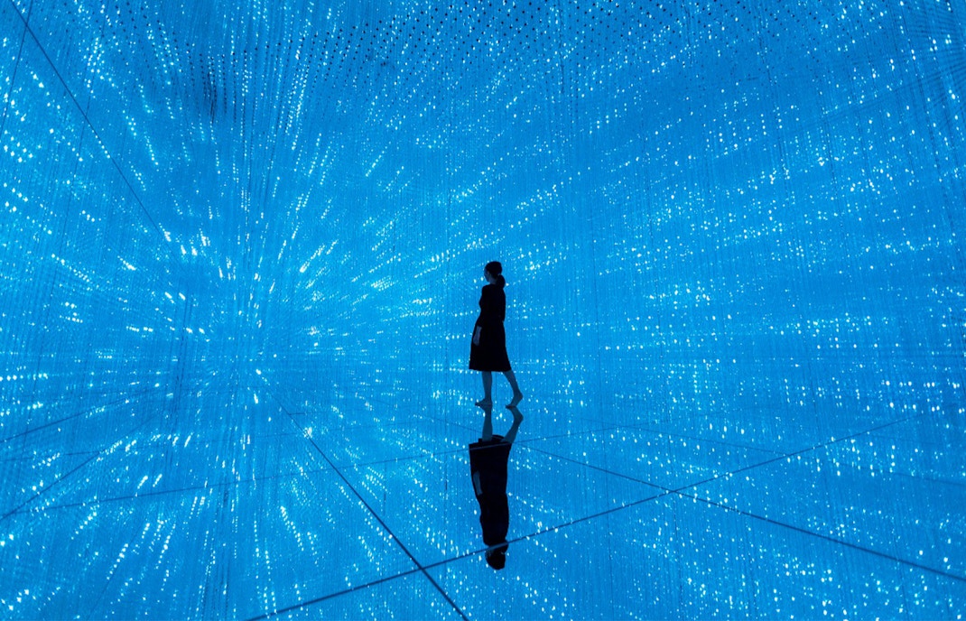 Person walking through digital light installation at TeamLab Planets Tokyo exhibit.