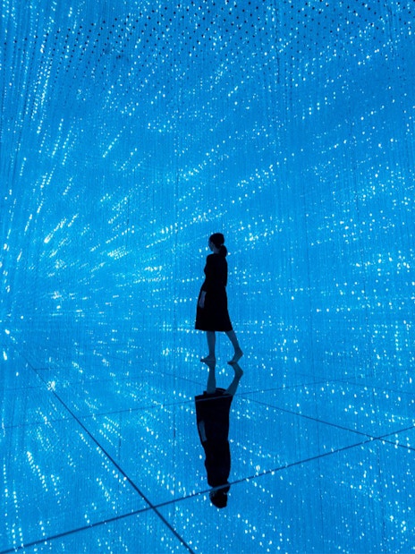 Person walking through digital light installation at TeamLab Planets Tokyo exhibit.