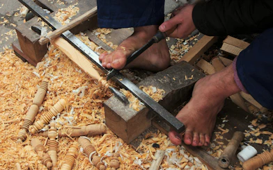 Woodworker carving with feet in Marrakech souk near Ben Youssef Medersa.