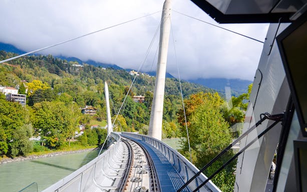 Hungerburg Funicular station view with tracks and lush green hills in Innsbruck, Austria.