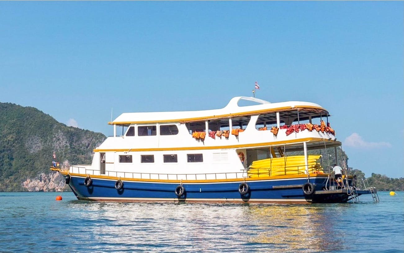 Tour boat with canoes on calm waters near Phuket, Thailand, part of John Gray's Sea Canoe day tour.
