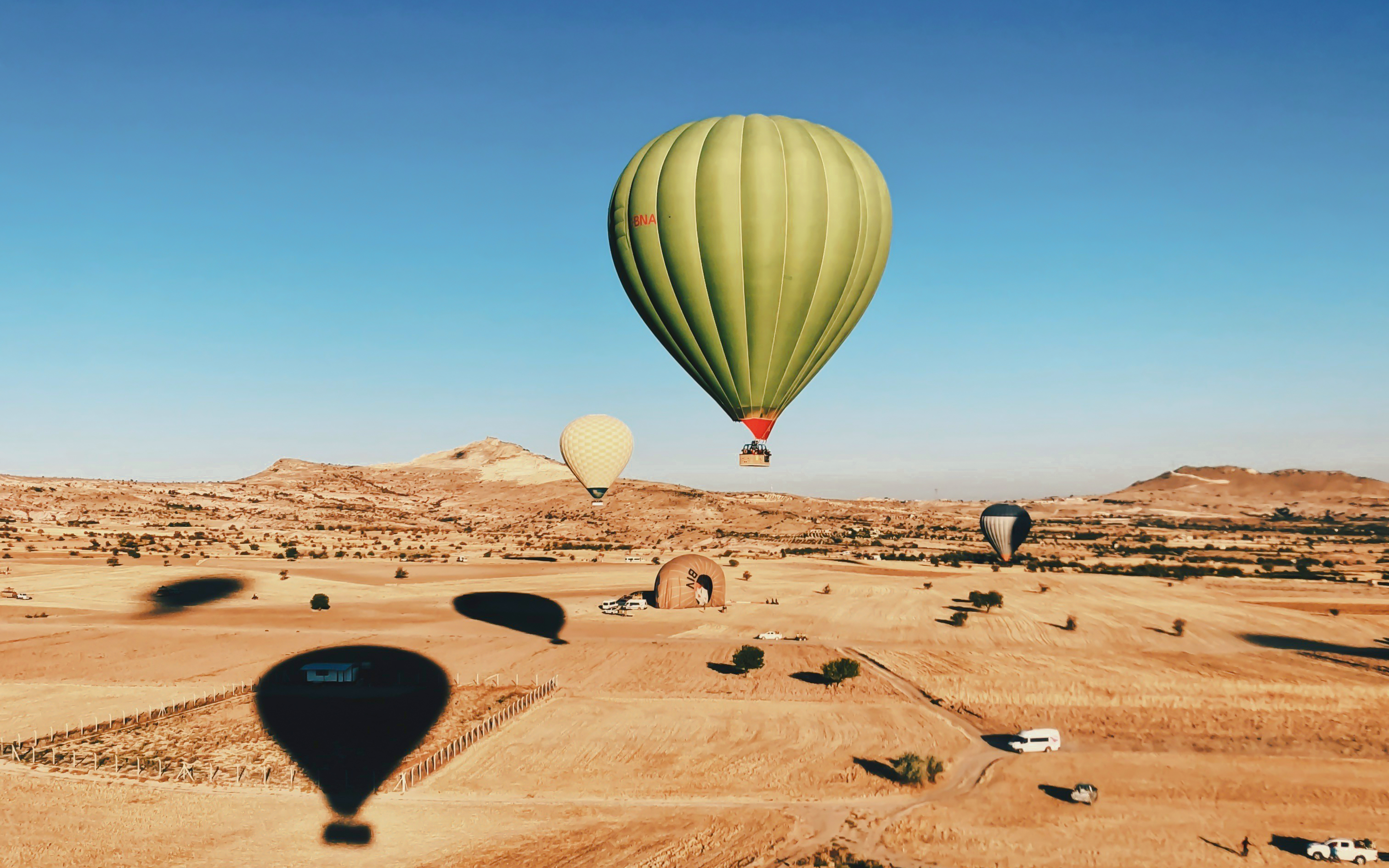 Green hot air balloon floating over desert landscape near Marrakech.
