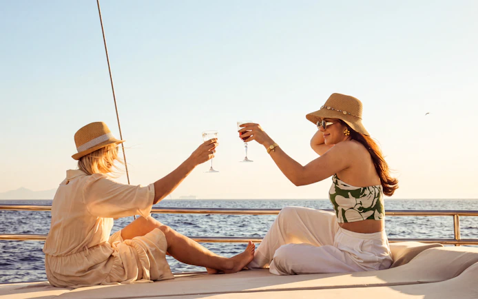 Women toasting with wine on a sunset cruise along Athens Riviera.