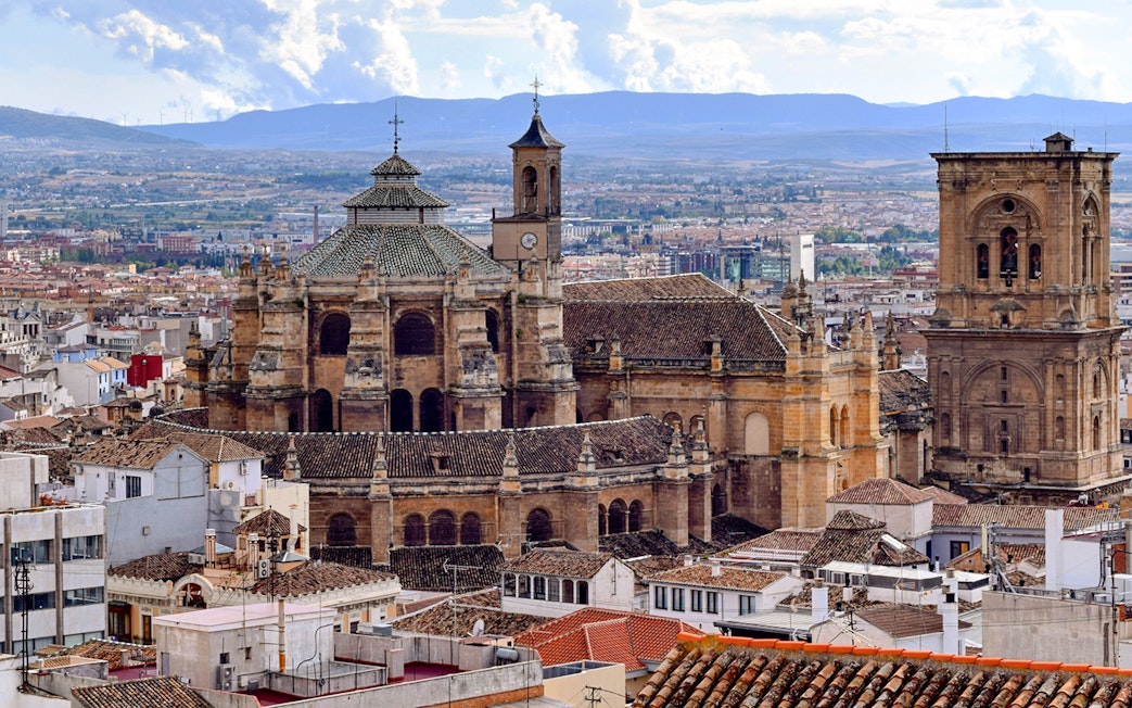 Granada Cathedral with cityscape and mountains in the background, Granada, Spain.