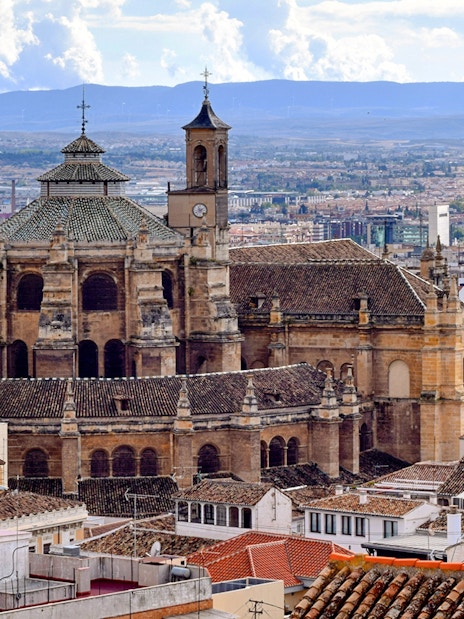 Granada Cathedral with cityscape and mountains in the background, Granada, Spain.
