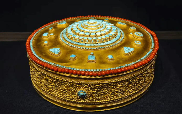 Golden ornate box with turquoise and coral inlays, displayed at National Palace Museum.
