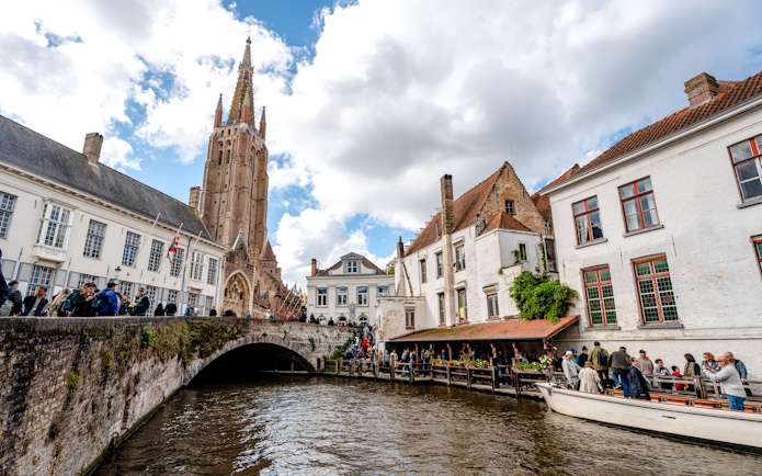 Scenic canal in Bruges, Belgium with Church of Our Lady in the background.