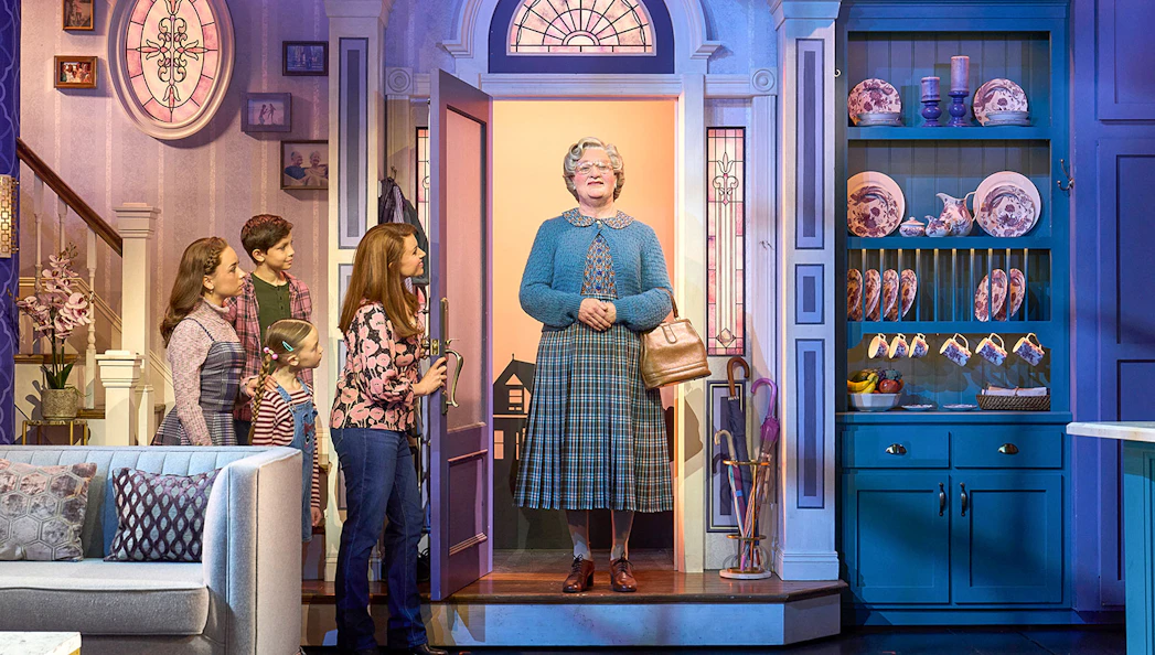 Family greeting Mrs. Doubtfire at the door in a cozy living room setting.
