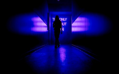 Silhouette walking towards neon sign inside Amaze Amsterdam.