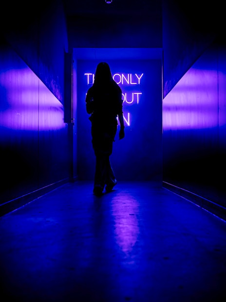 Silhouette walking towards neon sign inside Amaze Amsterdam.