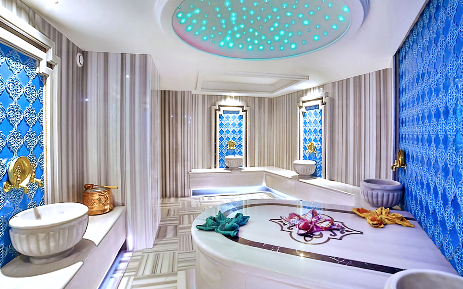 Interior of a private Turkish bath with marble basins and ornate blue tile walls.
