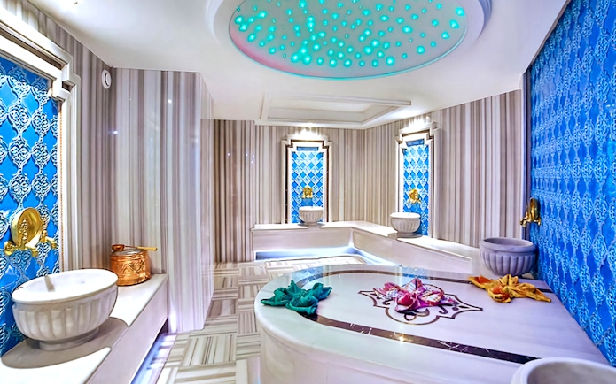 Interior of a private Turkish bath with marble basins and ornate blue tile walls.
