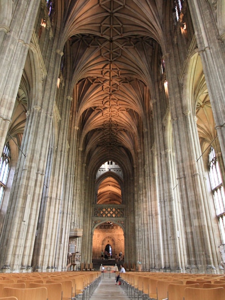 Interior of Canterbury Cathedral with vaulted ceilings and stained glass windows, part of the Canterbury and Dover tour.