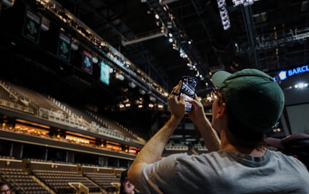 Person taking photo inside Barclays Center during guided tour, New York.