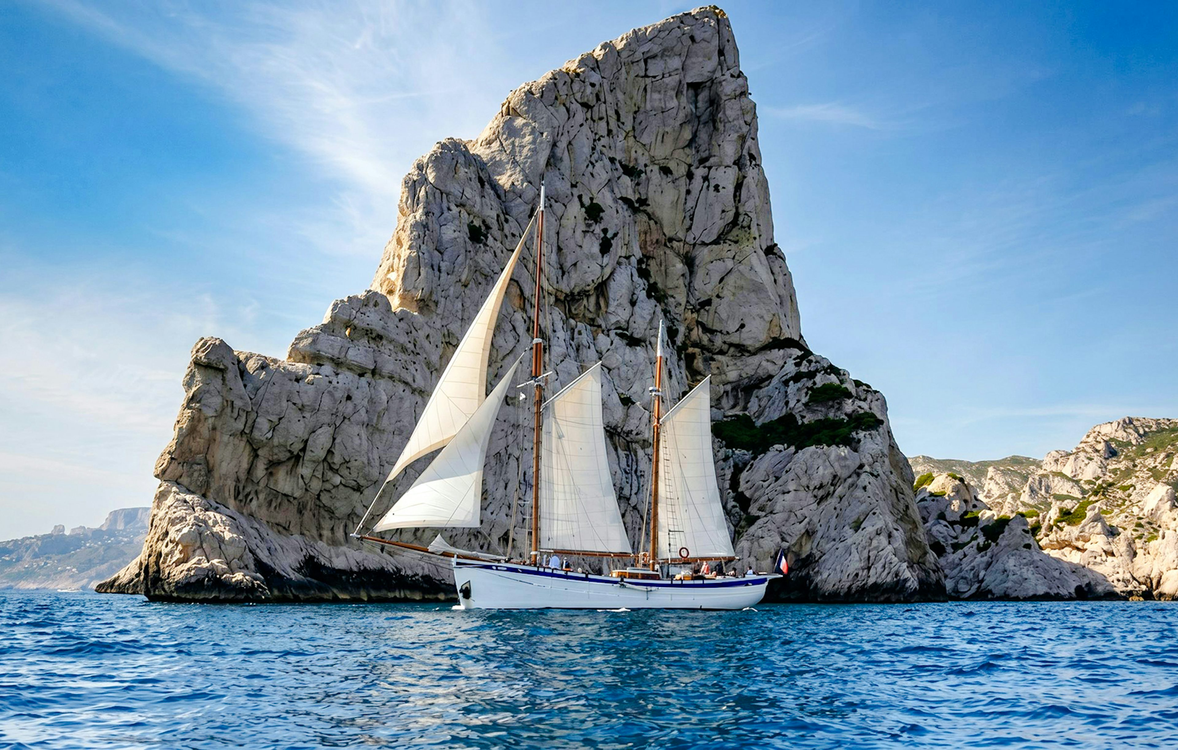 Sailing ship near rocky cliffs on Calanques Exploration Cruise.