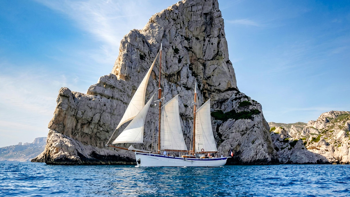 Sailing ship near rocky cliffs on Calanques Exploration Cruise.