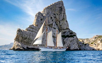 Sailing ship near rocky cliffs on Calanques Exploration Cruise.