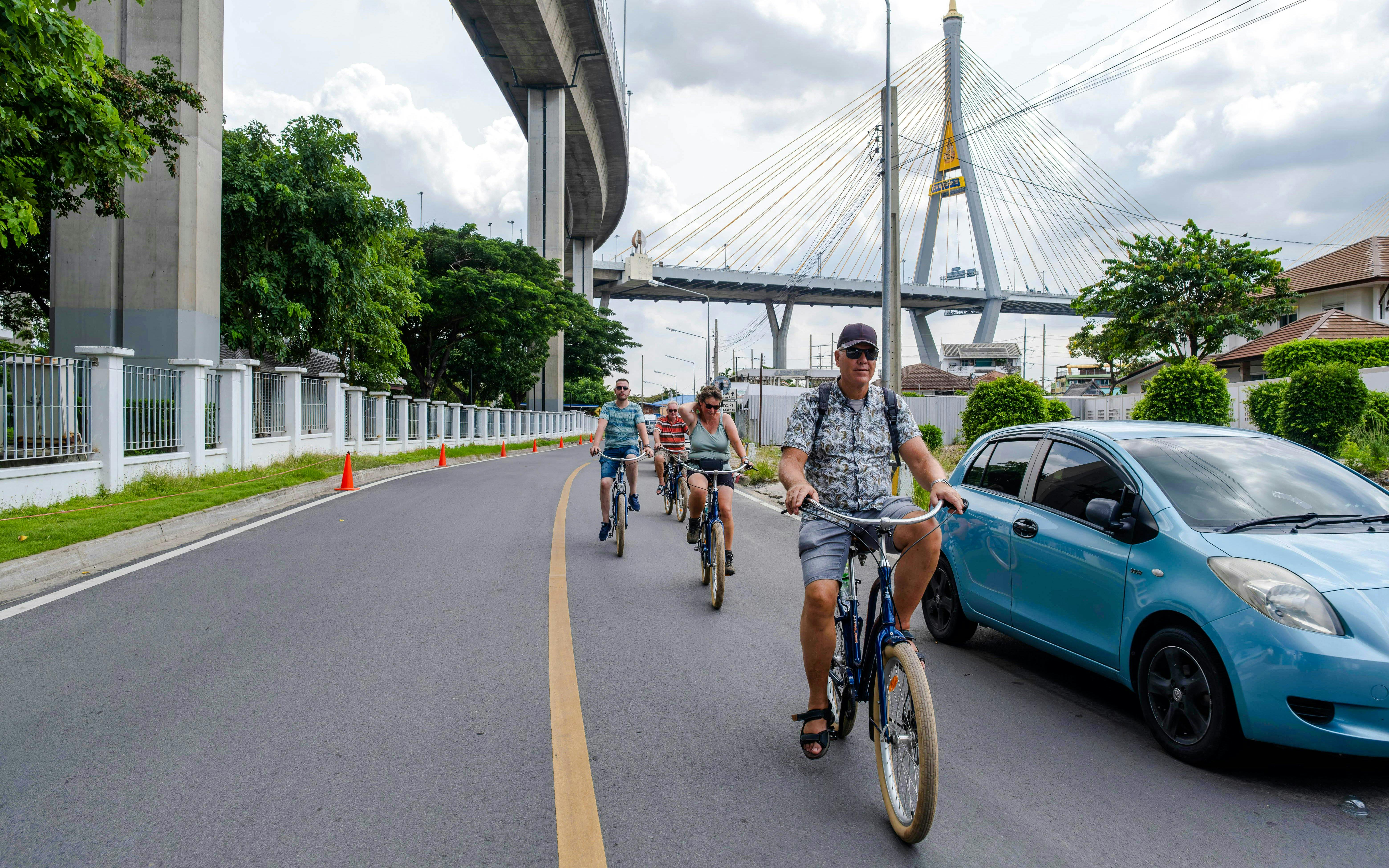 Cyclists riding under Bangkok's Bhumibol Bridge during a city tour.