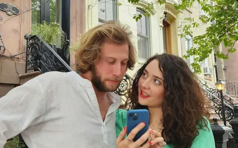 Couple using phone for Midtown Manhattan Greek Gods Adventure game in New York street.