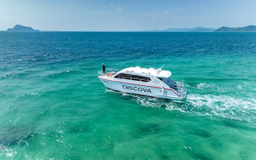 Speedboat cruising in Phang Nga Bay, Thailand with distant islands.